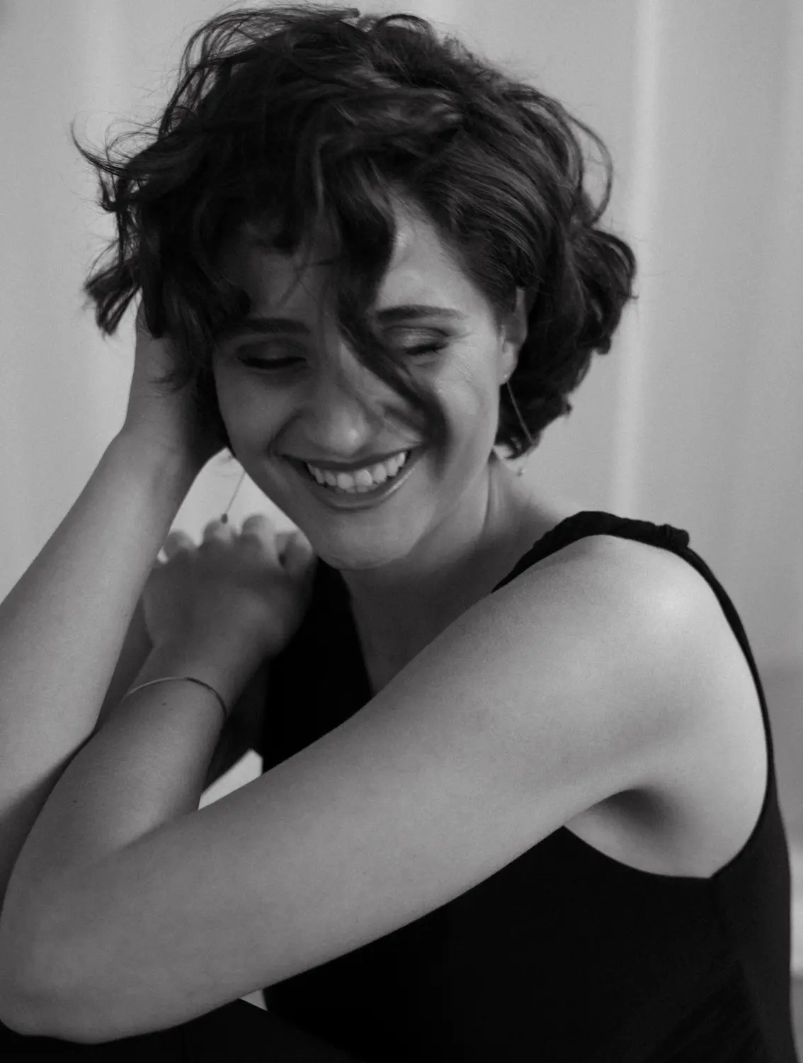 a young woman with short brown hair smiling in the right direction. the picture is in black and white