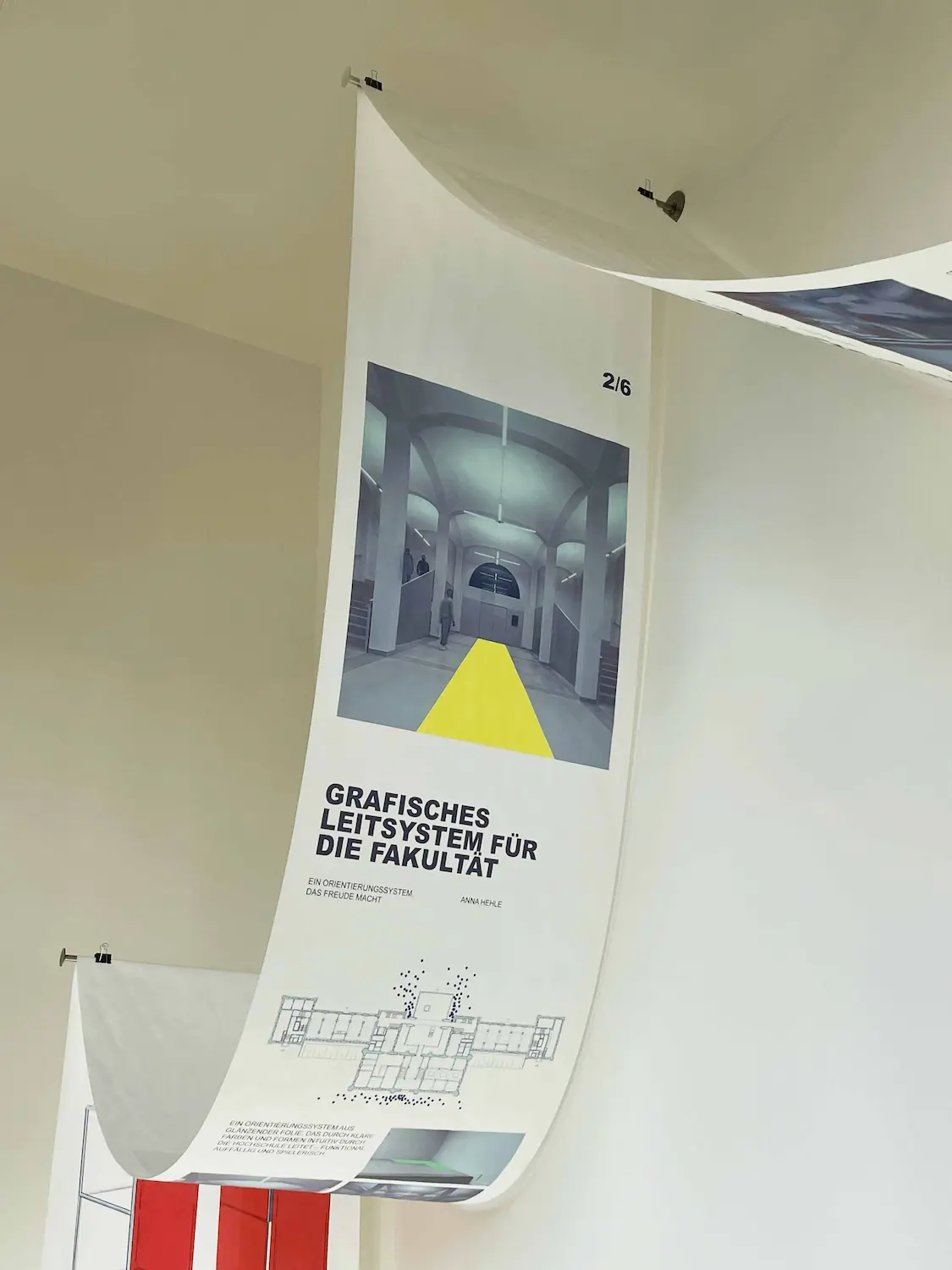 Visitors walking through an installation of flowing, U-shaped banners hung from the ceiling